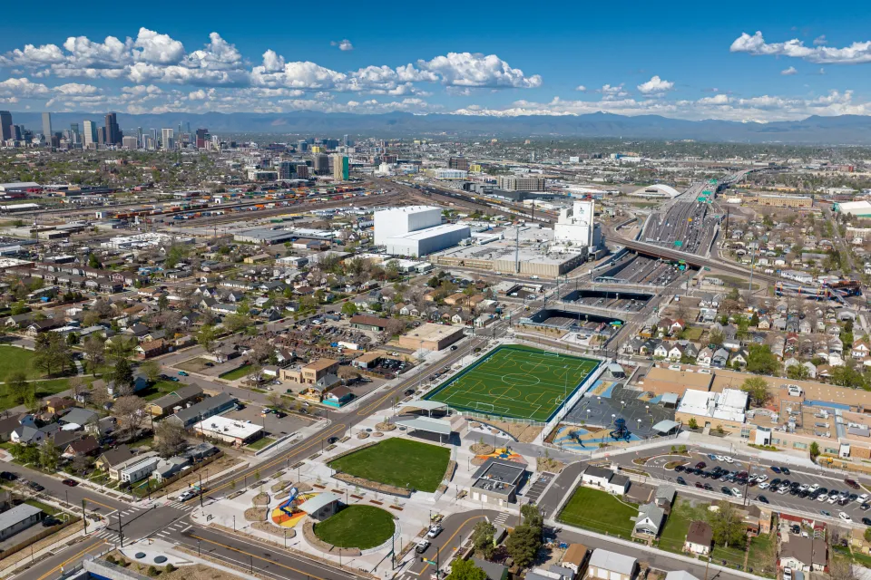 Aerial view of the cover park over I-70 and surrounding neighborhood with downtown Denver in background.